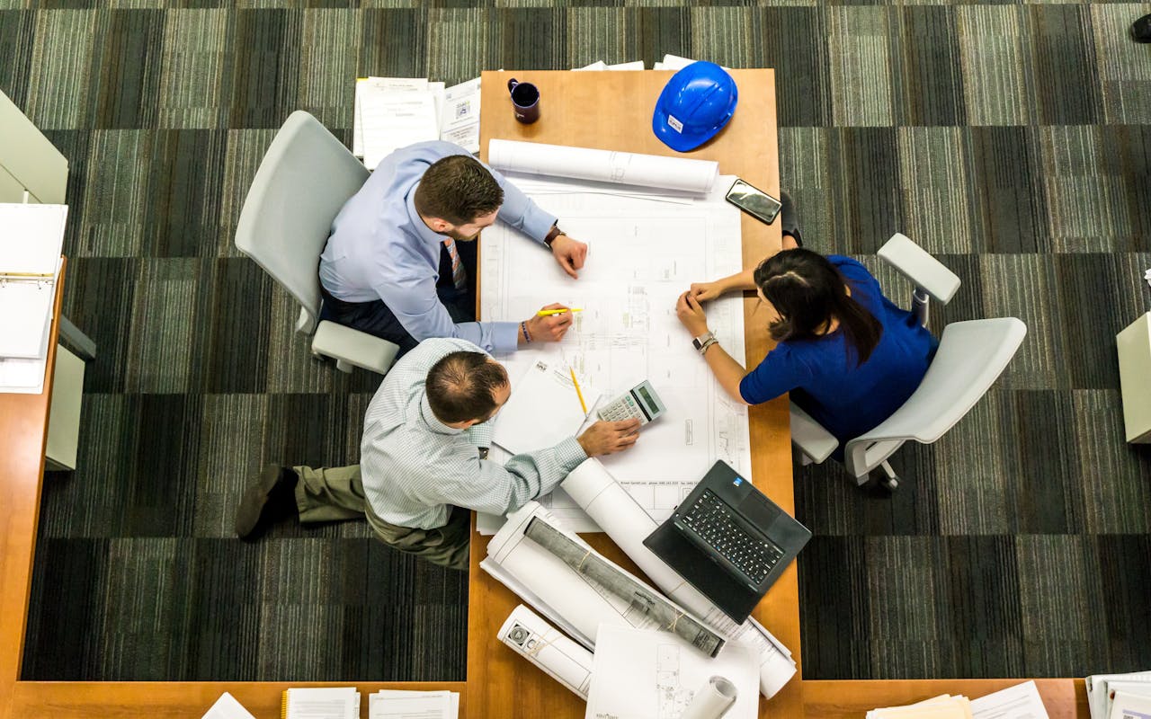 The Art of Drawing Readers In: Your attractive post title goes here Top view of a team working on construction plans in an office setting.